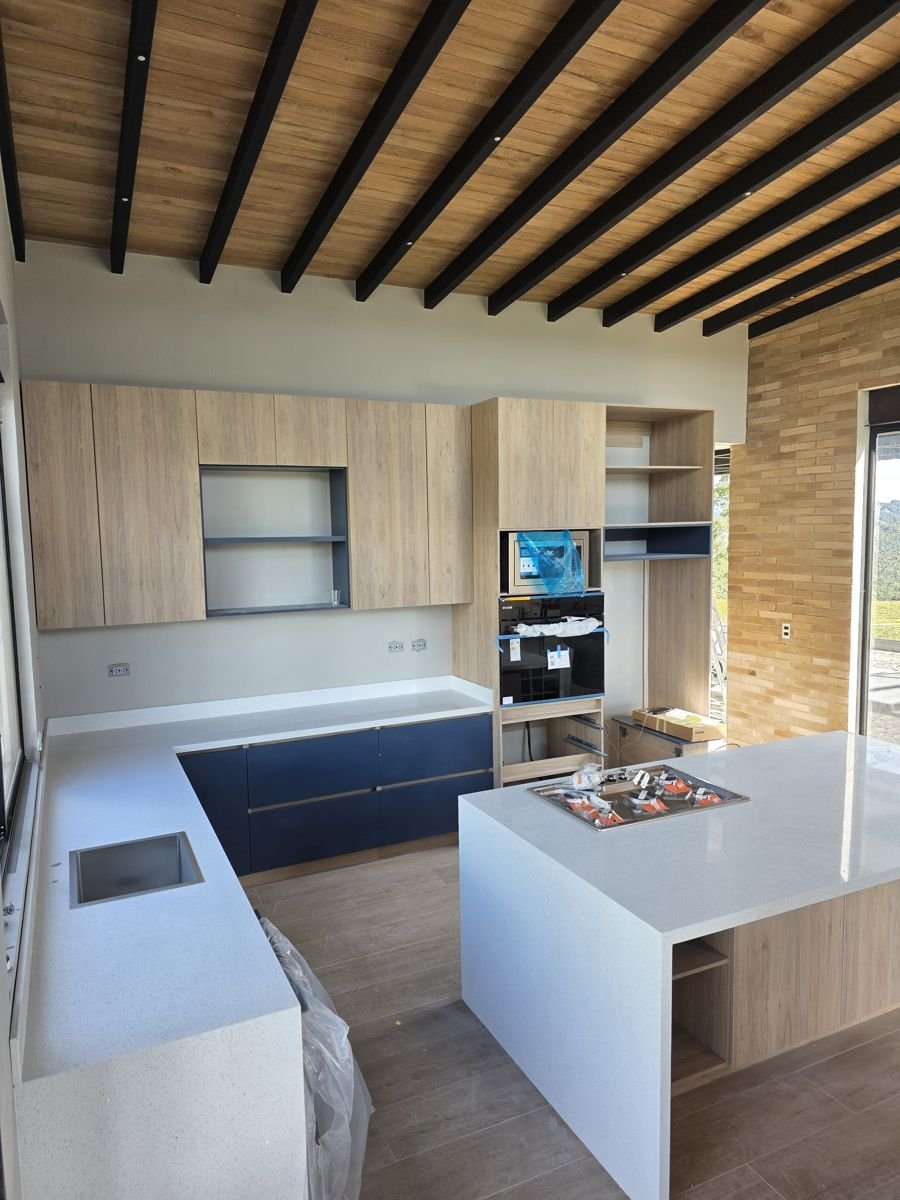 Cocina integral en madera con isla y mesón blanco
