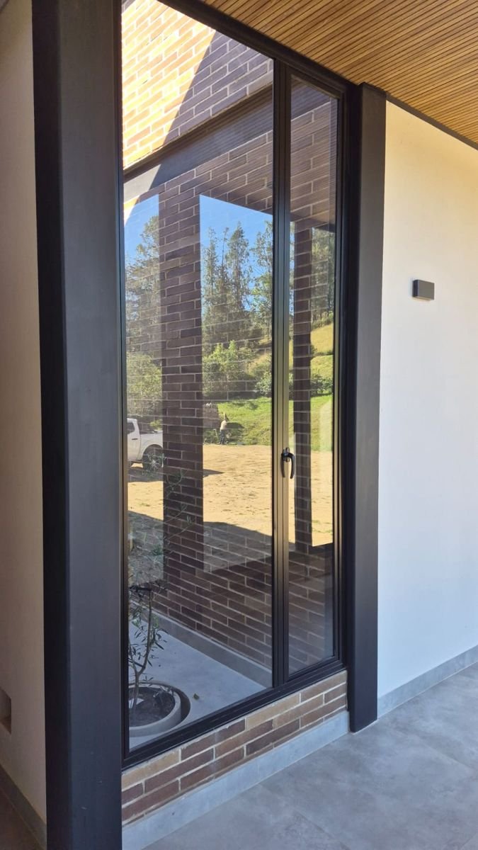 Puerta ventana corrediza con marco negro frente a un muro de ladrillo