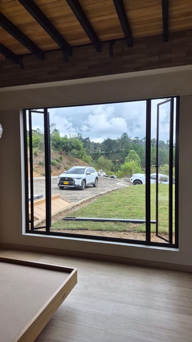 Ventana con hojas abatibles abiertas hacia el paisaje