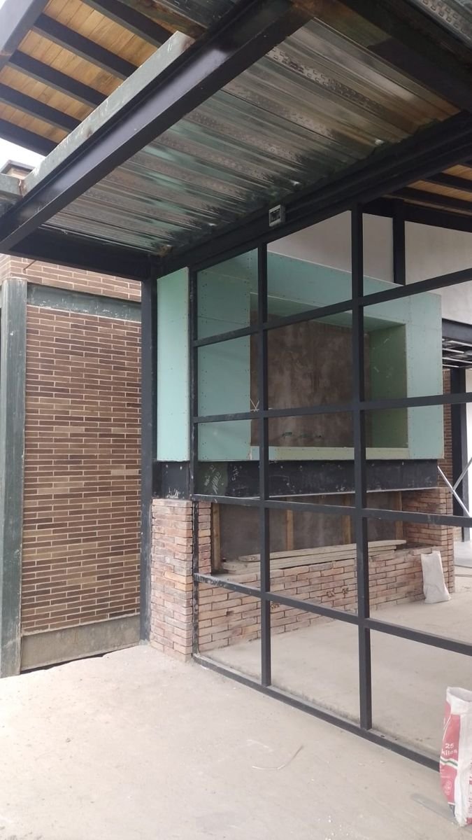Estructura con ventanal metálico y muro en drywall durante la obra