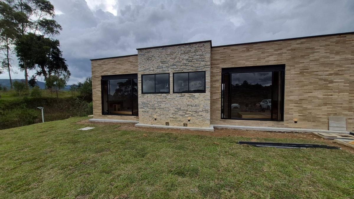 Vivienda en construcción con fachada en piedra y ventanas