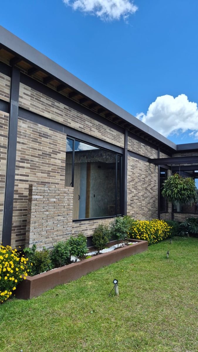 Fachada en ladrillo con ventanal y jardín