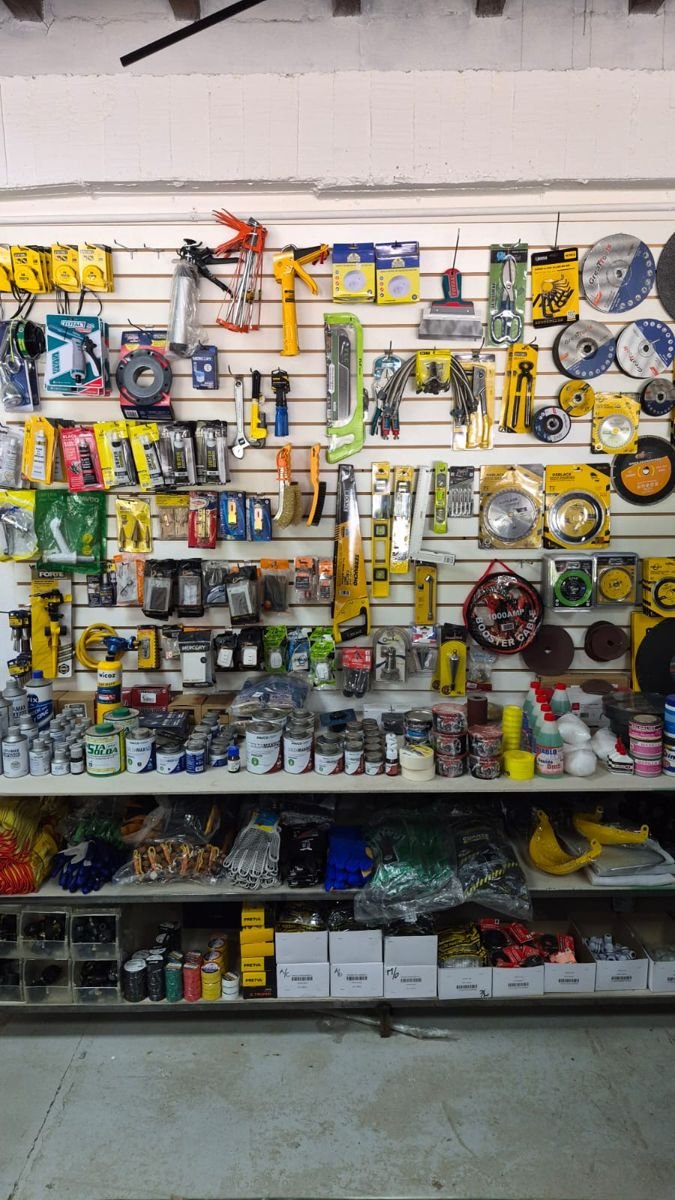 Pared de ferretería con herramientas, discos de corte, cintas y guantes